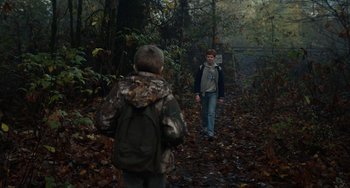 Movie still from “Antlers” (2021), directed by Scott Cooper – Two young boys are walking through the woods; Wide shot, Over the shoulder angle