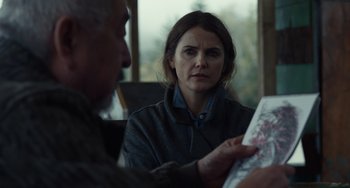 Movie still from “Antlers” (2021), directed by Scott Cooper – A woman is looking at a map while a man looks on; Medium shot, Over the shoulder angle
