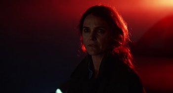 Movie still from “Antlers” (2021), directed by Scott Cooper – A woman in a black jacket standing in front of a red light; Close Up shot, Over the shoulder angle