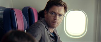 Movie still from “The Impossible” (2012), directed by J.A. Bayona – A person wearing glasses on a plane; Close Up shot, Over the shoulder angle