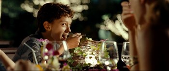 Movie still from “The Impossible” (2012), directed by J.A. Bayona – A young boy eating a salad at a dinner table; Close Up shot, Over the shoulder angle