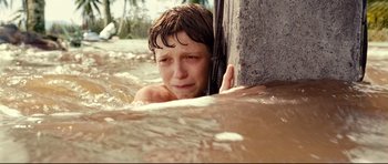 Movie still from “The Impossible” (2012), directed by J.A. Bayona – A young boy in a body of water holding onto an umbrella; Medium shot, High angle