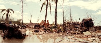 Movie still from “The Impossible” (2012), directed by J.A. Bayona – Three people sitting on a pile of debris in the middle of a river; Extreme Wide shot, High angle