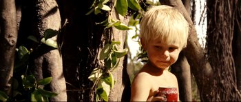 Movie still from “The Impossible” (2012), directed by J.A. Bayona – A little boy standing next to a tree holding a cup; Close Up shot, Low angle