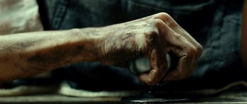 Movie still from “The Impossible” (2012), directed by J.A. Bayona – A person's hand is holding an object on a grinding wheel; Extreme Close Up shot, Overhead angle