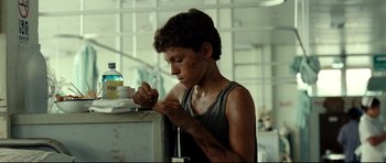 Movie still from “The Impossible” (2012), directed by J.A. Bayona – A young man writing on a piece of paper; Medium shot, Low angle