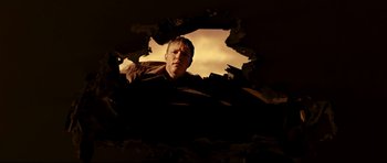 Movie still from “The Impossible” (2012), directed by J.A. Bayona – A man is looking through a hole in the wall; Medium shot, Low angle