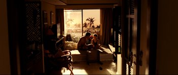 A man and a woman sitting on a bed in front of a window