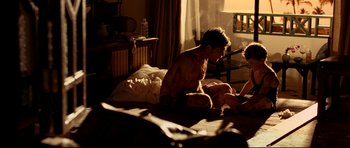 Movie still from “The Impossible” (2012), directed by J.A. Bayona – A man sitting on a bed next to a woman; Medium shot, Low angle
