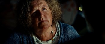 Movie still from “The Impossible” (2012), directed by J.A. Bayona – An older woman with curly blonde hair wearing a necklace; Close Up shot, Over the shoulder angle