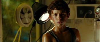 Movie still from “The Impossible” (2012), directed by J.A. Bayona – A young boy is standing in front of a lamp; Close Up shot, Low angle