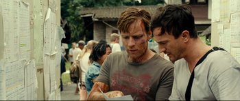 Movie still from “The Impossible” (2012), directed by J.A. Bayona – Two men looking at a piece of paper on the street; Close Up shot, Over the shoulder angle