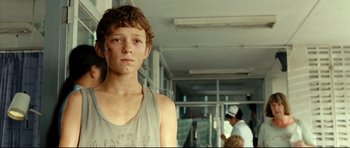 Movie still from “The Impossible” (2012), directed by J.A. Bayona – A young man standing in front of some people; Close Up shot, Over the shoulder angle