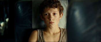 Movie still from “The Impossible” (2012), directed by J.A. Bayona – A young boy laying on a bed looking sad; Close Up shot, High angle