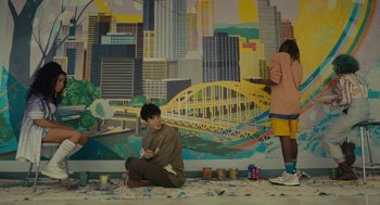 A man sitting on the ground in front of a mural