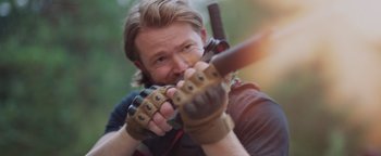 Movie still from “Apex” (2021), directed by Edward Drake – A man holding a gun and wearing gloves; Close Up shot, Over the shoulder angle