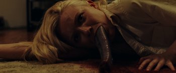 Movie still from “Appendage” (2023), directed by Anna Zlokovic – A woman laying on the ground with a fake penis in her mouth; Close Up shot, Low angle