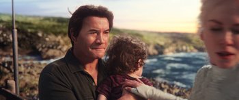 Movie still from “Aquaman” (2018), directed by James Wan – A person holding a child near a body of water; Close Up shot, Over the shoulder angle