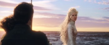Movie still from “Aquaman” (2018), directed by James Wan – A woman with long blonde hair standing on a beach; Medium shot, Over the shoulder angle