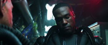 Movie still from “Aquaman” (2018), directed by James Wan – A man in a black suit is holding his head down; Close Up shot, Low angle