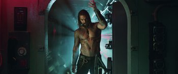 Movie still from “Aquaman” (2018), directed by James Wan – A man with a tattoo on his chest is standing in a tunnel; Medium shot, Low angle