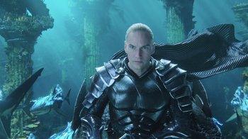 Movie still from “Aquaman” (2018), directed by James Wan – A man in armor is standing in the middle of the ocean; Medium shot, High angle