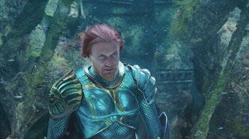 Movie still from “Aquaman” (2018), directed by James Wan – A man with red hair wearing a blue and gold armor; Medium shot, Over the shoulder angle