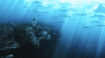Movie still from “Aquaman” (2018), directed by James Wan – A man is sitting on a rock under the water; Extreme Wide shot, High angle