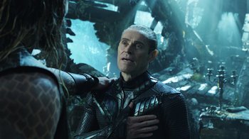 Movie still from “Aquaman” (2018), directed by James Wan – A man in a black suit standing next to a tree; Close Up shot, Over the shoulder angle