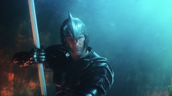 Movie still from “Aquaman” (2018), directed by James Wan – A man wearing a helmet and holding a sword; Medium shot, Low angle