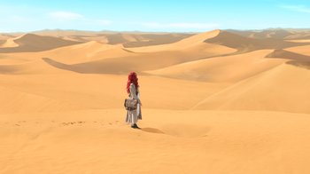 Movie still from “Aquaman” (2018), directed by James Wan – A woman with red hair is standing in the desert; Extreme Wide shot, High angle