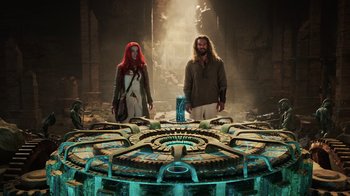 Movie still from “Aquaman” (2018), directed by James Wan – A woman and a man standing in front of a round table; Wide shot, Low angle