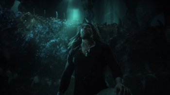 Movie still from “Aquaman” (2018), directed by James Wan – A man with long blonde hair is standing in the dark; Medium shot, High angle