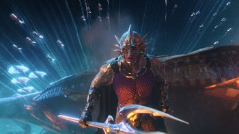 Movie still from “Aquaman” (2018), directed by James Wan – An image of a man holding a sword in the dark; Wide shot, Low angle