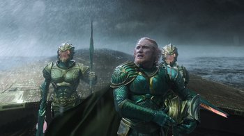 Movie still from “Aquaman” (2018), directed by James Wan – A group of men in armor standing next to each other in the rain; Medium shot, Low angle
