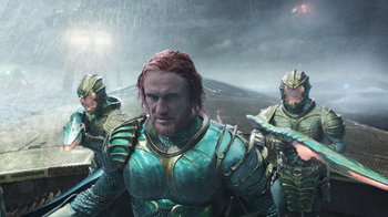 Movie still from “Aquaman” (2018), directed by James Wan – A group of men in armor standing next to each other in the rain; Medium shot, Over the shoulder angle