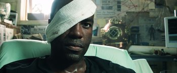 Movie still from “Aquaman” (2018), directed by James Wan – A man with bandages on his head and a bandage on his face; Close Up shot, Over the shoulder angle