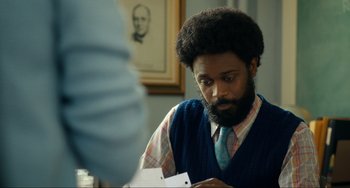 A man with a beard is looking down at a piece of paper