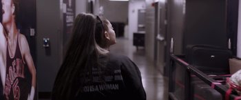Movie still from “Ariana Grande: Excuse Me, I Love You” (2020), directed by Paul Dugdale – A woman with long hair is standing in a hallway; Medium shot, Over the shoulder angle