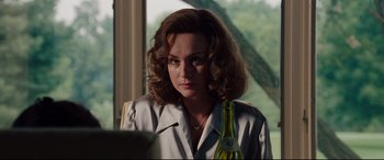 Movie still from “The Insider” (1999), directed by Michael Mann – A woman sitting at a table with a bottle of wine; Close Up shot, Over the shoulder angle