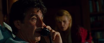 Movie still from “The Insider” (1999), directed by Michael Mann – A man talking on a phone while a woman looks on; Close Up shot, Low angle