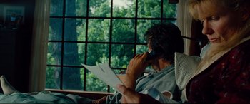 Movie still from “The Insider” (1999), directed by Michael Mann – A man sitting in a chair talking on a phone; Medium shot, Over the shoulder angle
