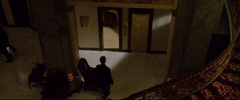 Movie still from “The Insider” (1999), directed by Michael Mann – A man sitting in a chair in a room; Extreme Wide shot, High angle
