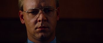 Movie still from “The Insider” (1999), directed by Michael Mann – A person wearing glasses and a suit; Close Up shot, Low angle