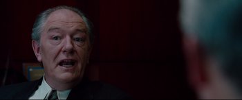 Movie still from “The Insider” (1999), directed by Michael Mann – An older man in a black suit is looking at the camera; Close Up shot, Low angle