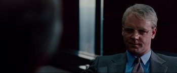 Movie still from “The Insider” (1999), directed by Michael Mann – A man sitting in a chair in front of a window; Close Up shot, Over the shoulder angle