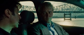 Movie still from “The Insider” (1999), directed by Michael Mann – A man sitting in the back seat of a car; Close Up shot, Over the shoulder angle