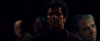 Movie still from “The Insider” (1999), directed by Michael Mann – A person wearing glasses and a black shirt; Close Up shot, Over the shoulder angle