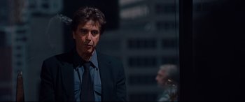 Movie still from “The Insider” (1999), directed by Michael Mann – A man wearing a suit and tie standing in front of a building; Close Up shot, Over the shoulder angle