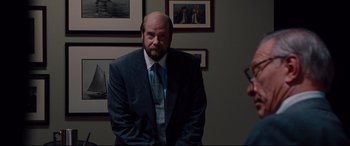 Movie still from “The Insider” (1999), directed by Michael Mann – A man in a suit and tie standing in a room; Medium shot, Over the shoulder angle